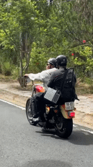 Motorcycle riders travel tree-lined road in Da Lat