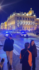 Pedestrians wait at crosswalk as police vehicles pass in Saint Petersburg