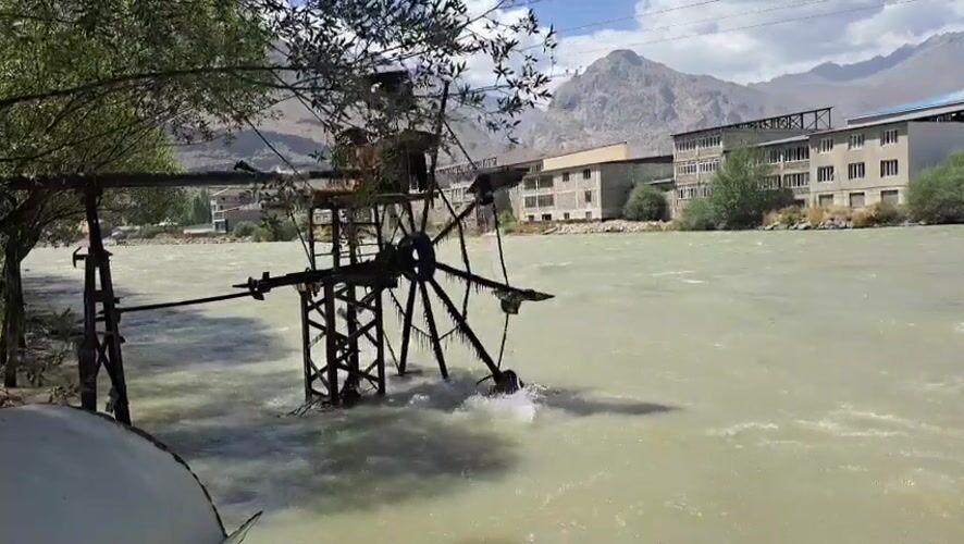 Ice-covered water wheel on a swift green river