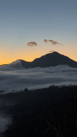 Tourist films misty mountain landscape at twilight in Kintamani