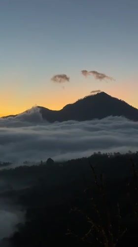 Tourist films misty mountain landscape at twilight in Kintamani