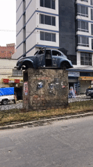 Damaged Volkswagen Beetle sits on concrete platform in La Paz median