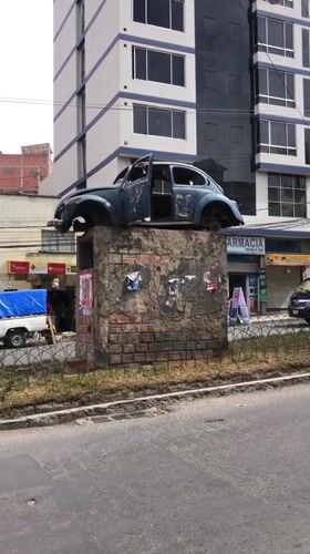 Damaged Volkswagen Beetle sits on concrete platform in La Paz median
