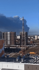 Dark smoke plume rises over urban area near apartments