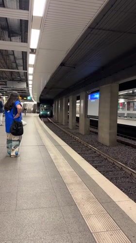 Woman waits as green subway train arrives Frankfurt station
