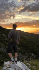 Man observes sunset landscape from rock in Asenovgrad