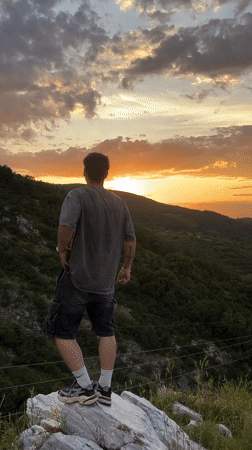 Man observes sunset landscape from rock in Asenovgrad