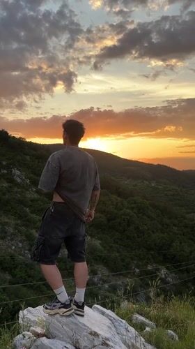 Man observes sunset landscape from rock in Asenovgrad