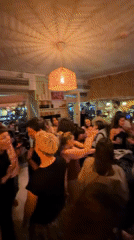 Mixed-age crowd dances in dimly lit Milan bar