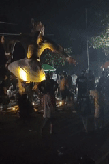 Nighttime cultural event with performers and effigy in Kanigoro