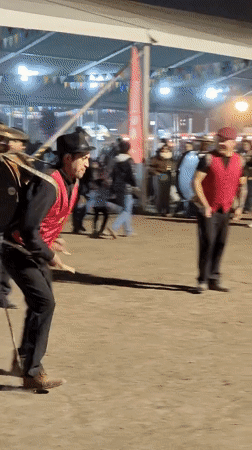Street drummer performs for crowd wearing harness-mounted bass drum