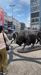 Visitors photograph bronze bull statue in Kadıköy public square