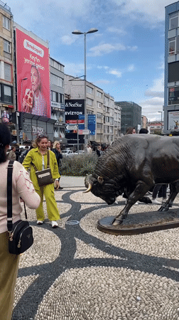 Visitors photograph bronze bull statue in Kadıköy public square