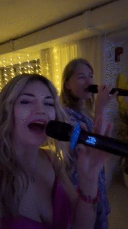 Two women enjoy karaoke night in Boreti, Montenegro