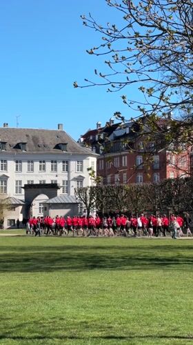 Teenagers in red shirts run through Copenhagen park near castle