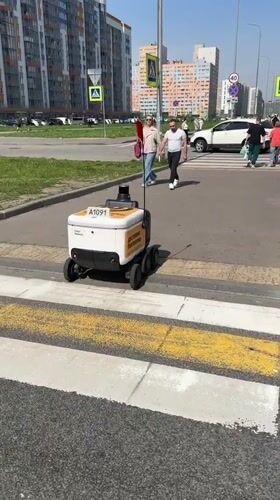 Delivery robot crosses crosswalk with pedestrians in Murino, Russia