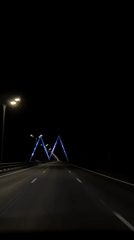 Car travels illuminated highway with colored overhead structures in Kazan