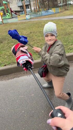 Boy plays with umbrellas on wet walkway in Dmitrov