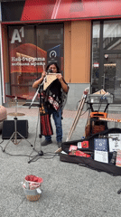 Street musicians perform under pink umbrellas in pedestrian district