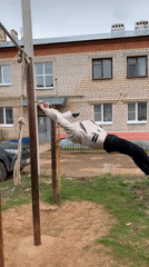 Person performs outdoor gymnastics on utility pole bar in Russia