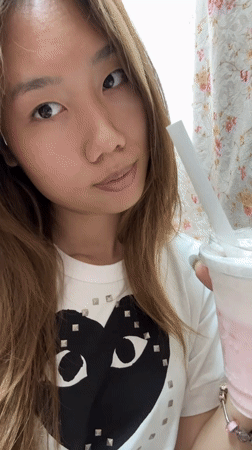 Woman takes selfies, drinks pink beverage in Chongqing bedroom