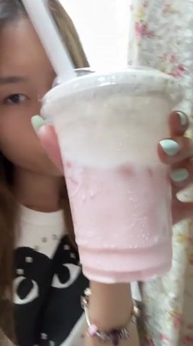 Woman takes selfies, drinks pink beverage in Chongqing bedroom