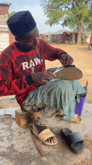 Cobbler repairs sandal outdoors in Adankolo, Nigeria