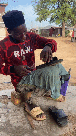 Cobbler repairs sandal outdoors in Adankolo, Nigeria