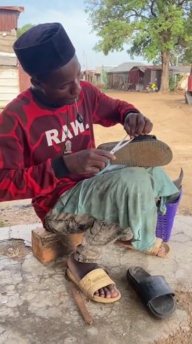 Cobbler repairs sandal outdoors in Adankolo, Nigeria