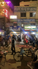 Nighttime street activity captured in Dhaka's illuminated commercial district