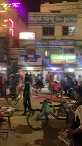 Nighttime street activity captured in Dhaka's illuminated commercial district