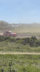 Red race car speeds on dirt track in Serbia