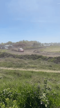 Red race car speeds on dirt track in Serbia