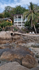 Woman sits on rocky beach in Choeng Mon, Thailand