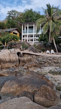 Woman sits on rocky beach in Choeng Mon, Thailand