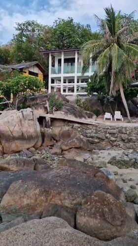 Woman sits on rocky beach in Choeng Mon, Thailand