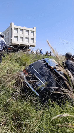 Vehicle off road in tall grass, recovery underway in rural Kyrgyzstan
