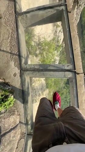 Tourist visits glass bridge overlook in Yongding District mountains