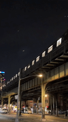 NYC elevated train rolls through the night above city streets