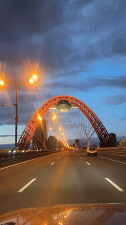 Evening traffic flows across Moscow's Zhivopisny Bridge at dusk