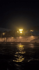 Eiffel Tower glows gold over a crowded Seine riverbank at night