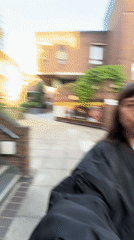 Woman in bomber jacket smiles while walking in London