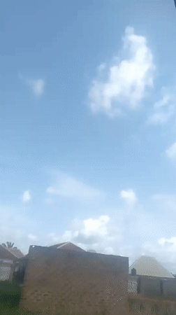 Brick building under a clear blue sky with scattered clouds