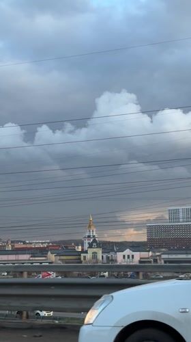Vehicle passenger films church steeple, overcast skyline in Kotelniki