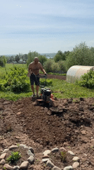 Man tills garden soil on sunny day in Russia