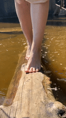Barefoot crossing over water near deteriorating bridge in Chaikovsky