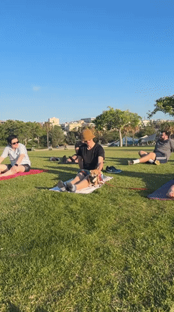 Outdoor yoga on a Tel Aviv seaside lawn, late afternoon.