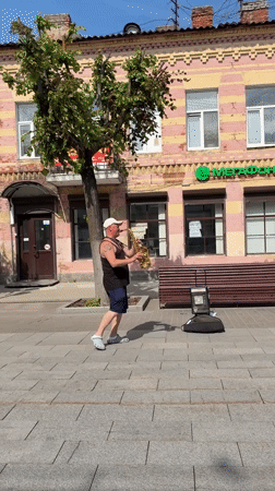 Saxophone player on a Gatchina sidewalk near an Orthodox church