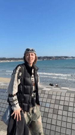 Woman films at Kamakura beach on sunny morning
