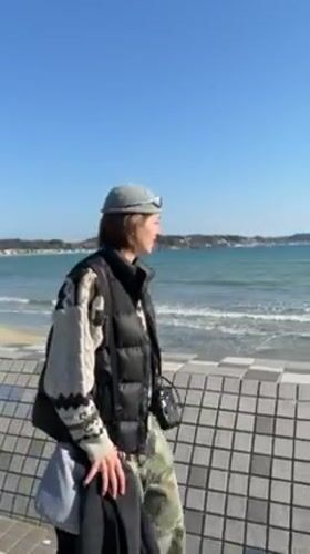 Woman films at Kamakura beach on sunny morning